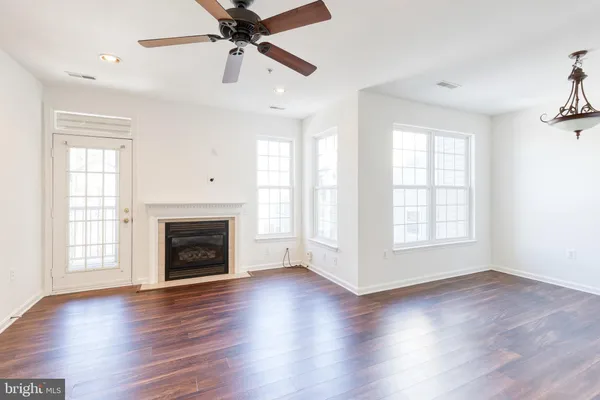 an empty room with wooden floor fireplace and windows