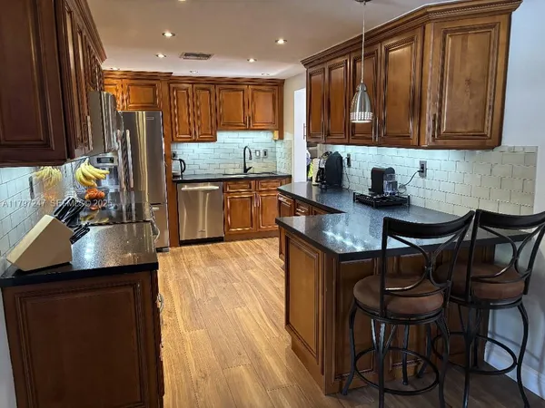 a kitchen with stainless steel appliances granite countertop a stove a sink and a microwave