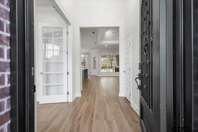 a view of a hallway with wooden floor and a bathroom