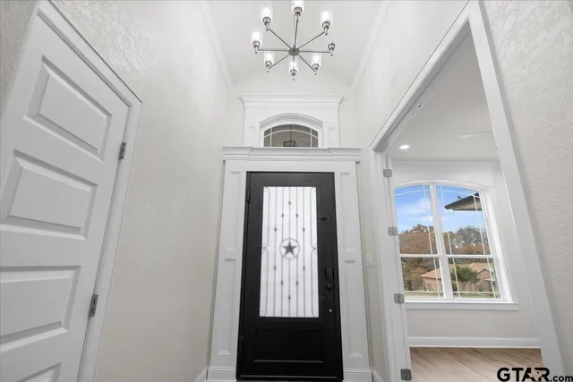 a view of a hallway with windows and chandelier