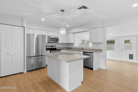 a kitchen with stainless steel appliances granite countertop a refrigerator a stove a sink and a microwave