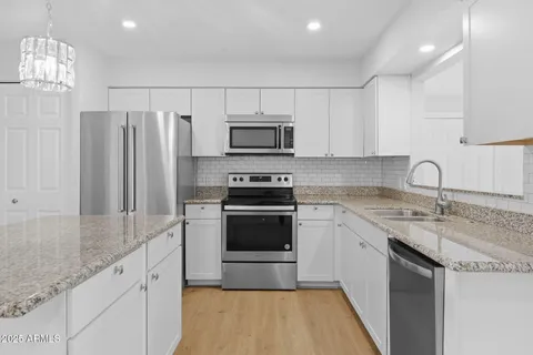 a kitchen with stainless steel appliances granite countertop a stove a sink and a refrigerator