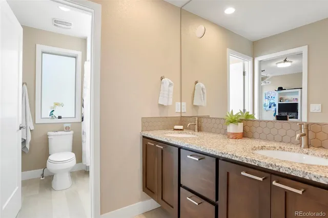 a bathroom with a granite countertop sink a toilet and a mirror