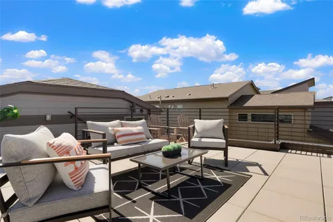 a roof deck with table and chairs and potted plants