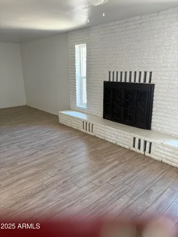 a view of an empty room with wooden floor and a fireplace