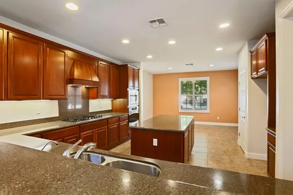 a kitchen with stainless steel appliances granite countertop a refrigerator a stove and a sink with wooden floor