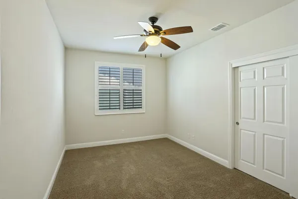 an empty room with a ceiling fan and a window