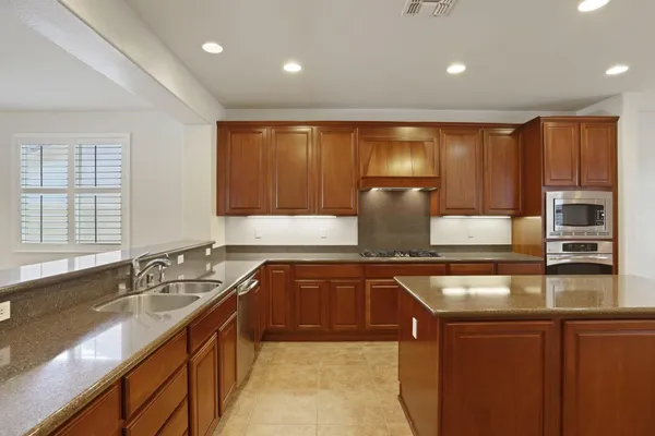 a kitchen with kitchen island granite countertop a sink stainless steel appliances and cabinets