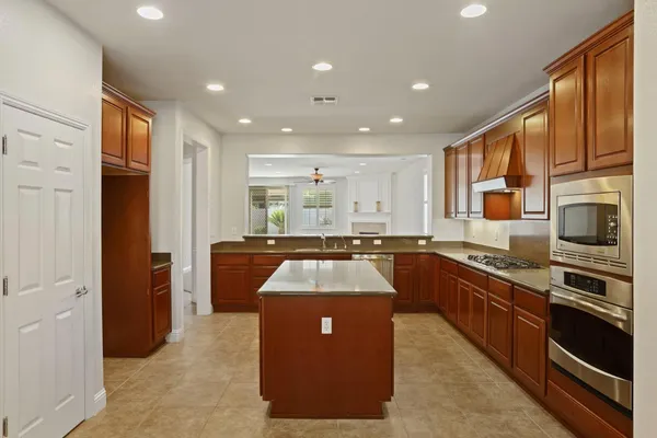 a kitchen with stainless steel appliances granite countertop refrigerator a sink dishwasher a oven with wooden cabinets and floors