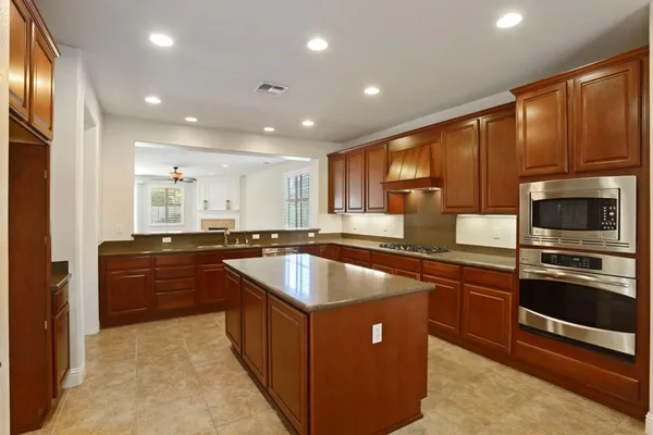 a large kitchen with stainless steel appliances wooden cabinets and a stove top oven