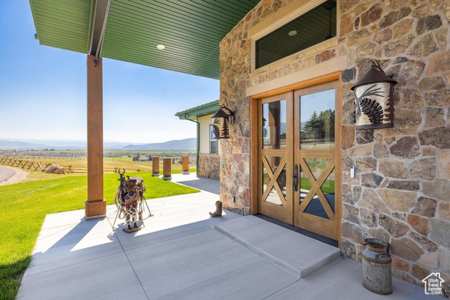 6117 North Rocky Ridge Road Peoa, UT 84061 - Photo 8 of 83 View of exterior entry featuring a rural view, a mountain view, a lawn, and french doors