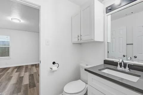 a bathroom with a granite countertop sink mirror vanity and toilet
