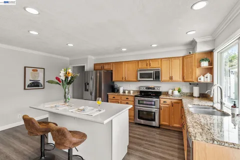 a kitchen with stainless steel appliances a stove top oven a sink dishwasher and a dining table with wooden floor