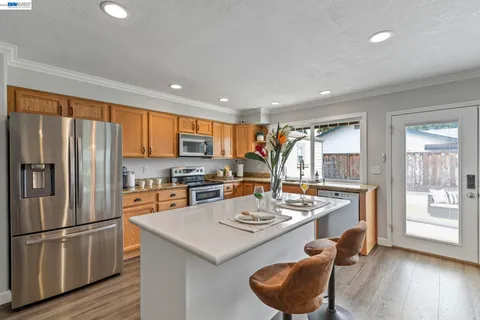 a kitchen with stainless steel appliances granite countertop a refrigerator a stove a sink a dining table and chairs