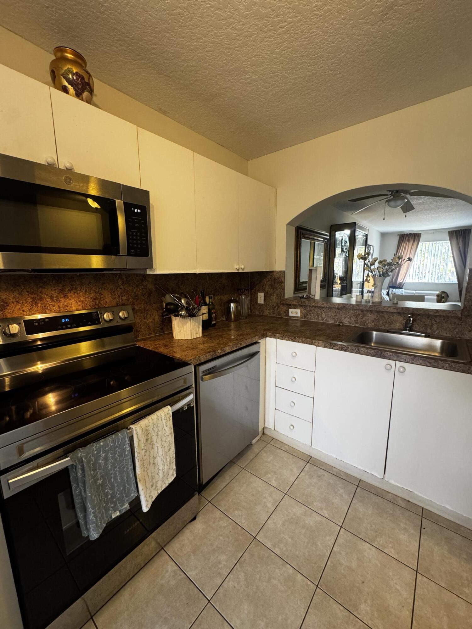 3810 North Jog Road, Unit 105 Royal Palm Beach, FL 33411 - Photo 17 of 26 a kitchen with granite countertop a stove and a sink