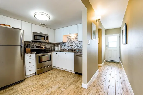 a kitchen with white cabinets and stainless steel appliances