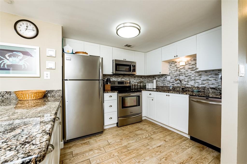 4799 South Atlantic Avenue, Unit 3030 Ponce Inlet, FL 32127 - Photo 3 of 26 a kitchen with granite countertop a refrigerator stove and microwave