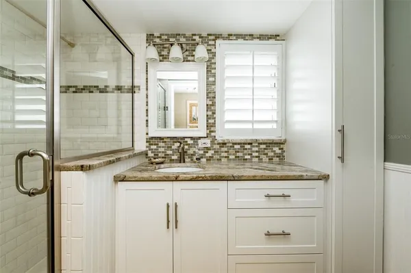 a bathroom with a granite countertop sink a mirror and a shower