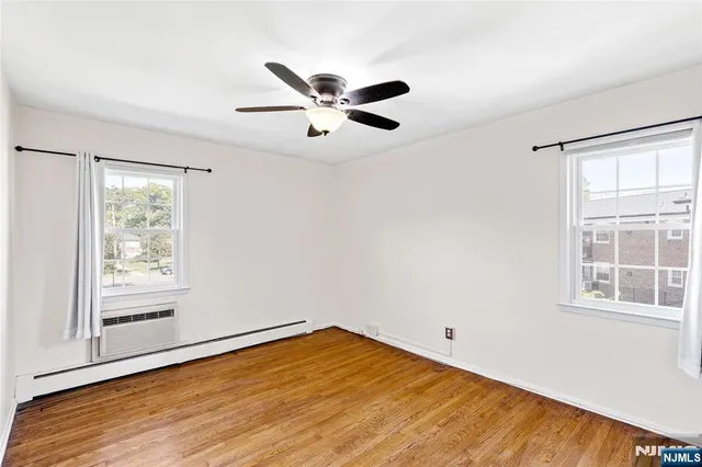 a view of empty room with wooden floor and fan