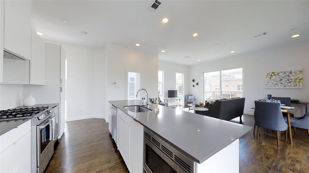 4905 Live Oak Street, Unit D Dallas, TX 75206 - Photo 11 of 19 a large kitchen with kitchen island a stove a sink a dining table and chairs