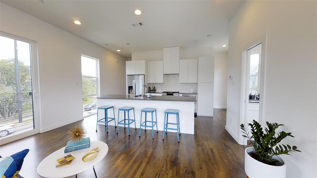 4905 Live Oak Street, Unit D Dallas, TX 75206 - Photo 6 of 19 a kitchen with stainless steel appliances granite countertop a refrigerator a microwave oven a dining table and chairs with wooden floor