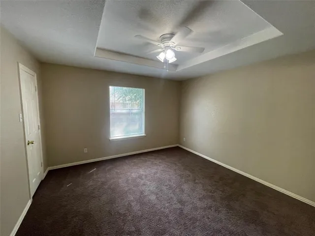 an empty room with a chandelier fan and windows