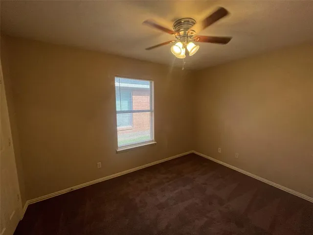 an empty room with a chandelier fan and windows
