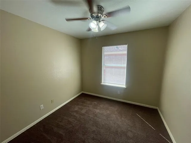 an empty room with a chandelier fan and windows