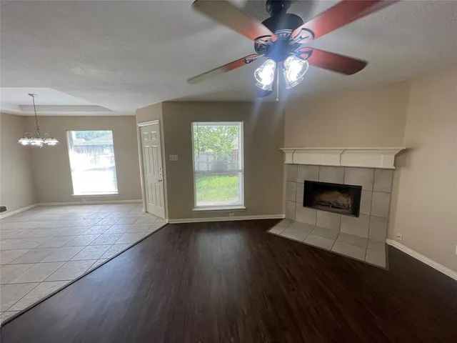 an empty room with wooden floor a chandelier fan and windows