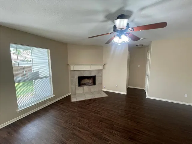 a view of a livingroom with a fireplace a chandelier fan and wooden floor