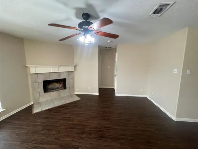 a view of an empty room with wooden floor a fireplace and a window