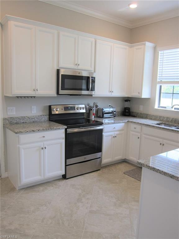 1170 Genovesa Court, Unit 12 Naples, FL 34113 - Photo 11 of 18 a kitchen with granite countertop white cabinets and white stainless steel appliances