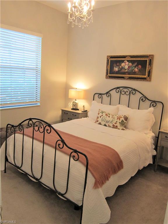 1170 Genovesa Court, Unit 12 Naples, FL 34113 - Photo 6 of 18 a bedroom with a bed and a chandelier