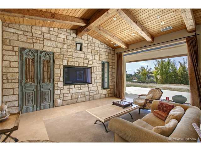 3520 Fortuna Ranch Road Encinitas, CA 92024 - Photo 2 of 11 Vaulted Wood Ceiling With Hand Hewed Beams, Stone Wall With Circa 1800 Antique Hand Carved French Doors To Access Surround Sound Equipment, Recessed Ceiling Speakers, Extra Large Fireplace, 3 10'x4' Floor To Ceiling Lift Glide Glass Pocket Doors.