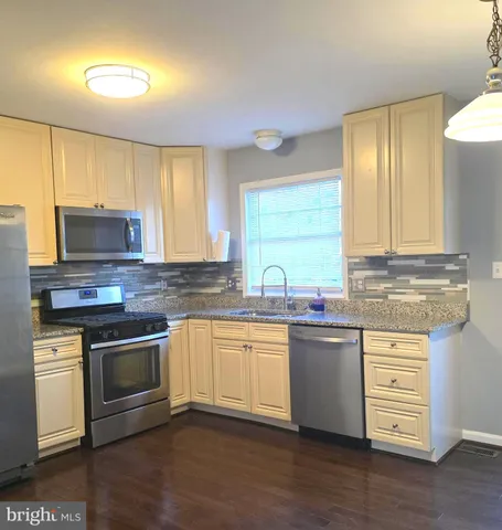 a kitchen with stainless steel appliances granite countertop wooden floors and white cabinets