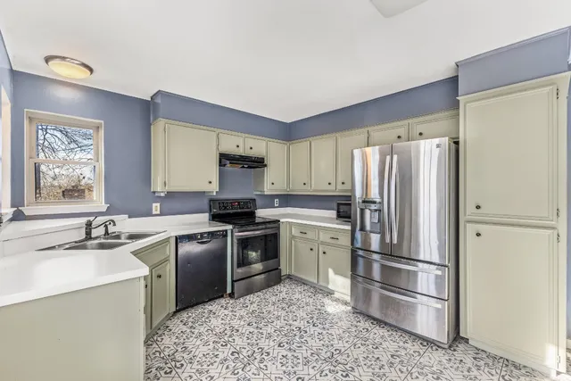 a utility room with fridge and wooden floor