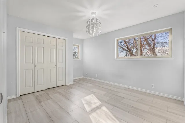 a bathroom with a granite countertop toilet a sink a mirror a shower a window and vanity