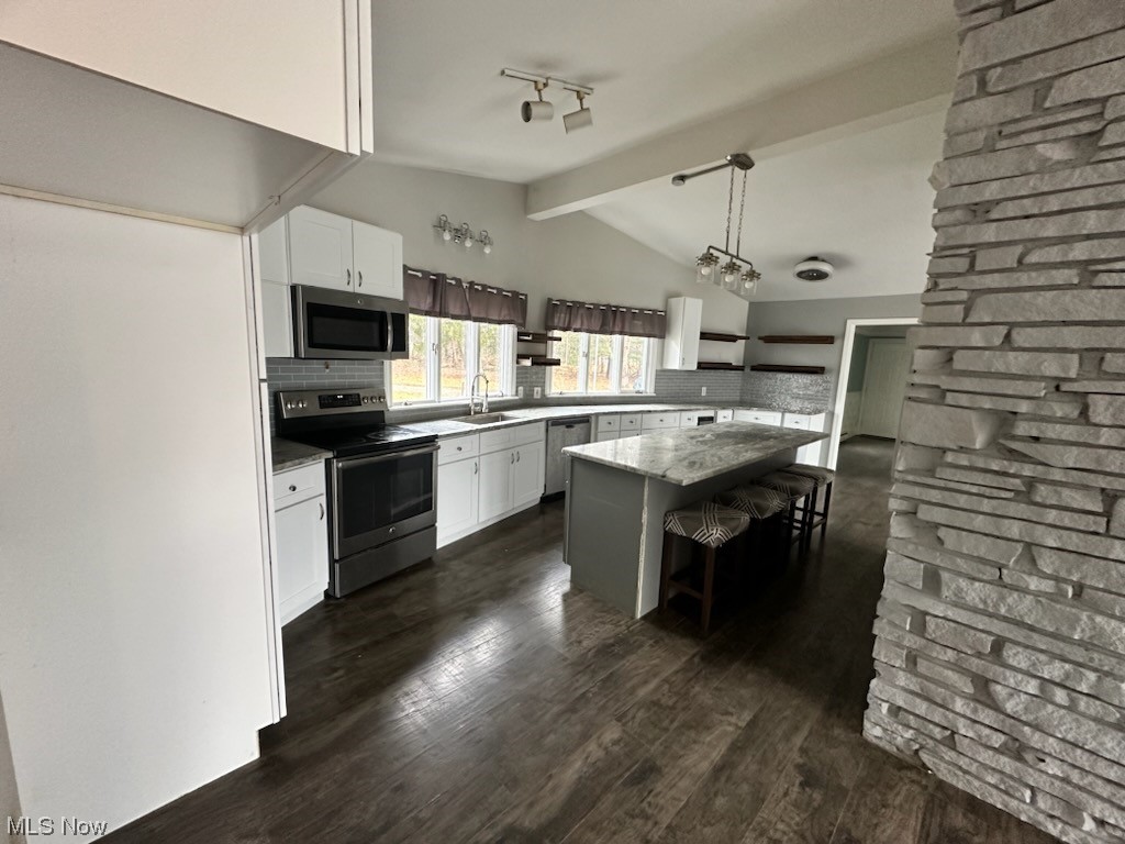 4396 Rootstown Road Rootstown, OH 44272 - Photo 11 of 21 Kitchen featuring vaulted ceiling with beams, backsplash, white cabinetry, a breakfast bar, and stainless steel appliances