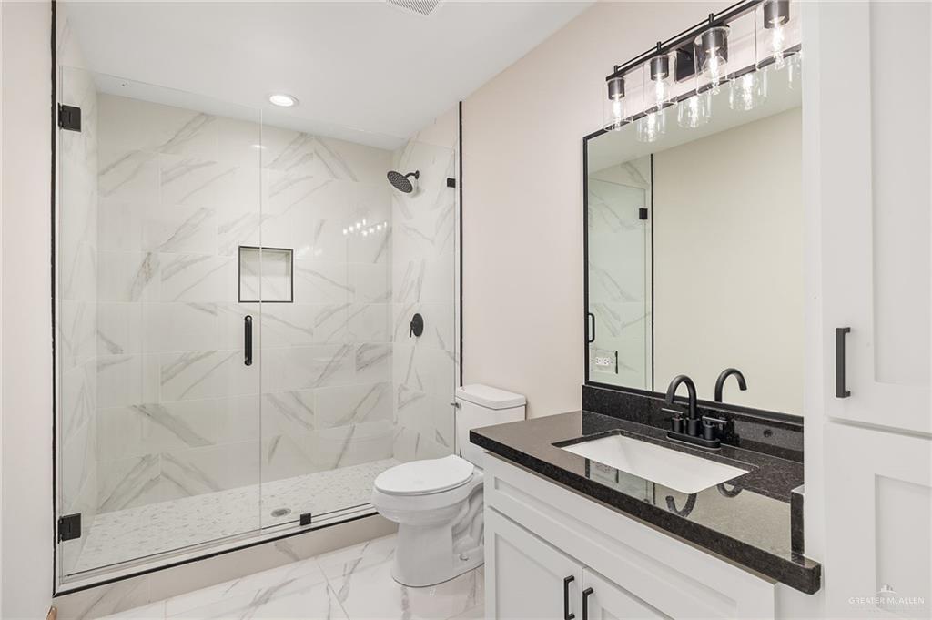 348 Coro Street Donna, TX 78537 - Photo 6 of 17 a bathroom with a granite countertop sink a toilet and shower