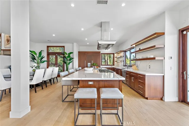 a dining hall with stainless steel appliances kitchen island granite countertop a table chairs and a living room view