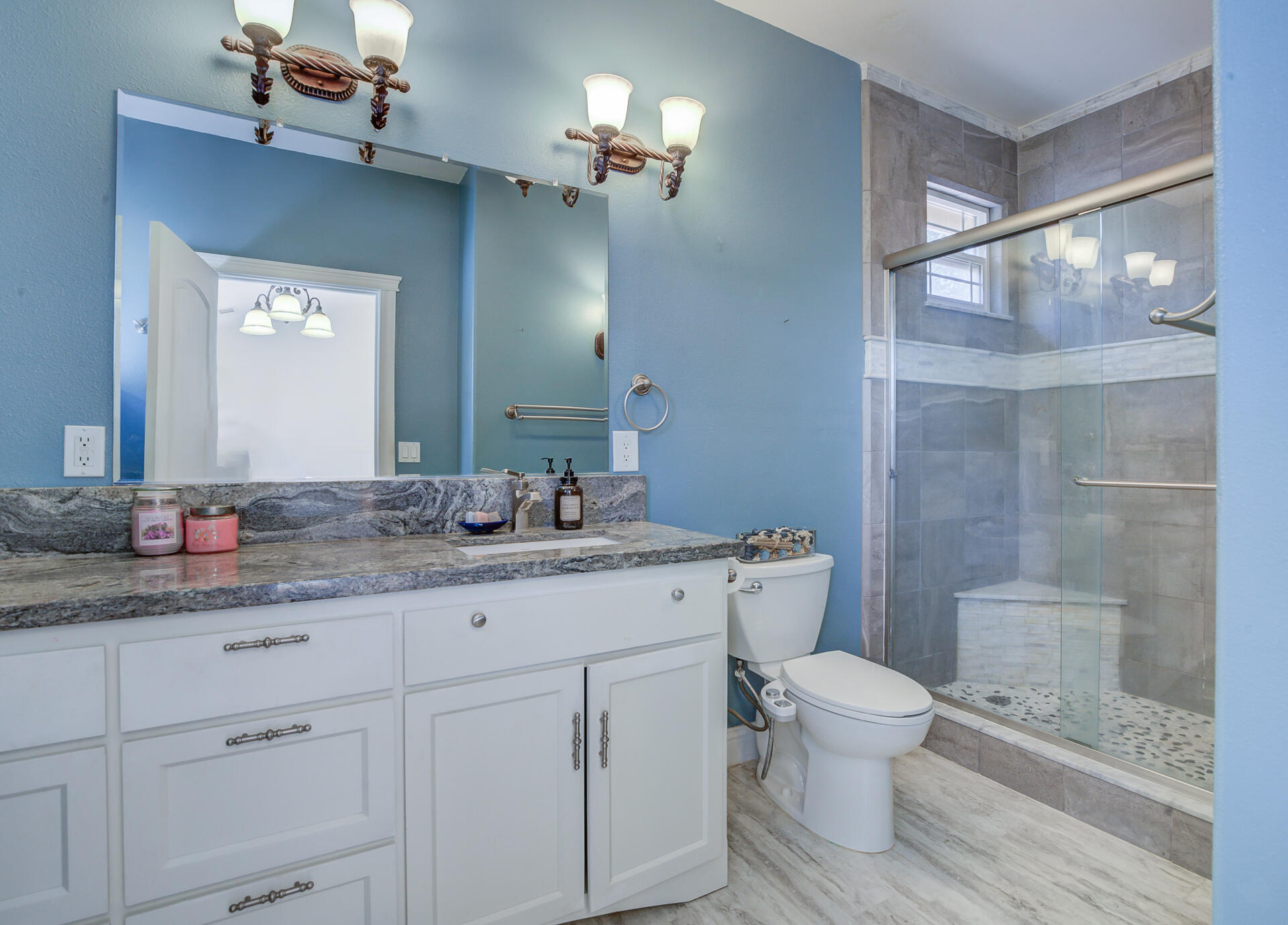 5146 Surrey Drive Redding, CA 96002 - Photo 33 of 57 a bathroom with a granite countertop sink a toilet a mirror and shower