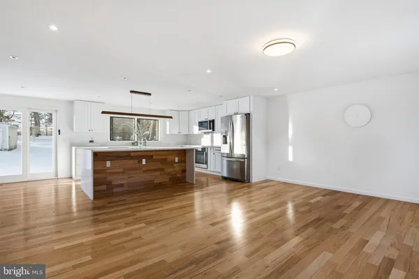 a room with stainless steel appliances kitchen island wooden floors and center island