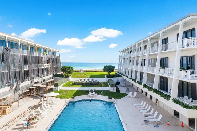 a front view of a building with garden and trees