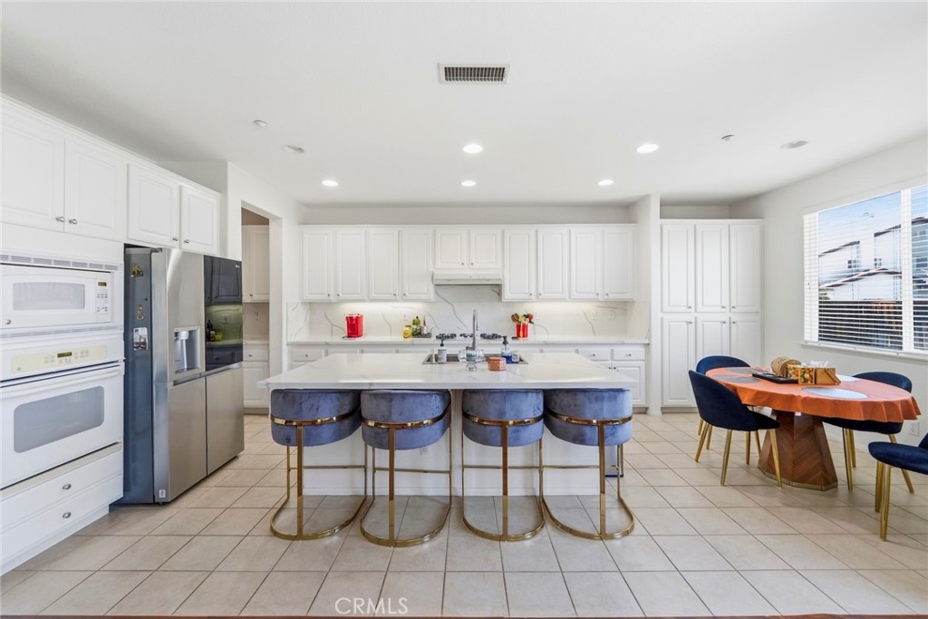 1663 Naranjo Court Redlands, CA 92374 - Photo 19 of 59 a kitchen with stainless steel appliances kitchen island granite countertop a table chairs sink and cabinets
