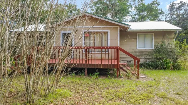 a view of backyard with large trees and wooden fence