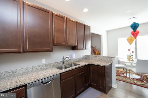 a kitchen with kitchen island granite countertop a sink cabinets and wooden floor