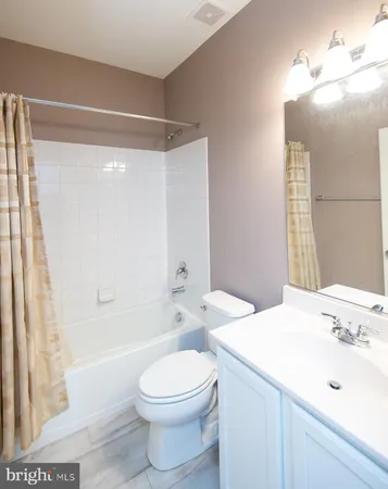 a bathroom with a bathtub shower sink vanity mirror and toilet