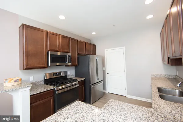 a kitchen with stainless steel appliances granite countertop a stove a sink and a refrigerator