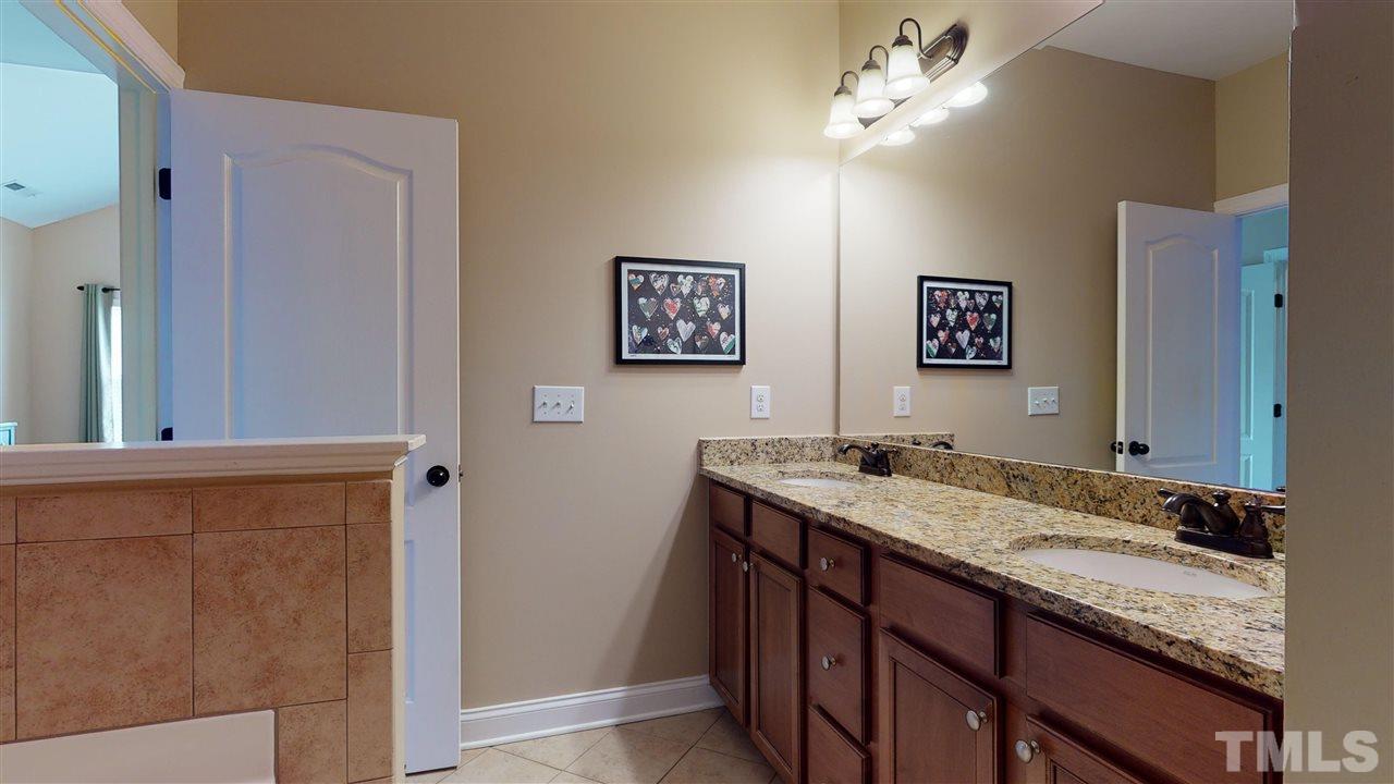 628 Democracy Street Raleigh, NC 27603 - Photo 19 of 26 a bathroom with a granite countertop sink a mirror and a shower