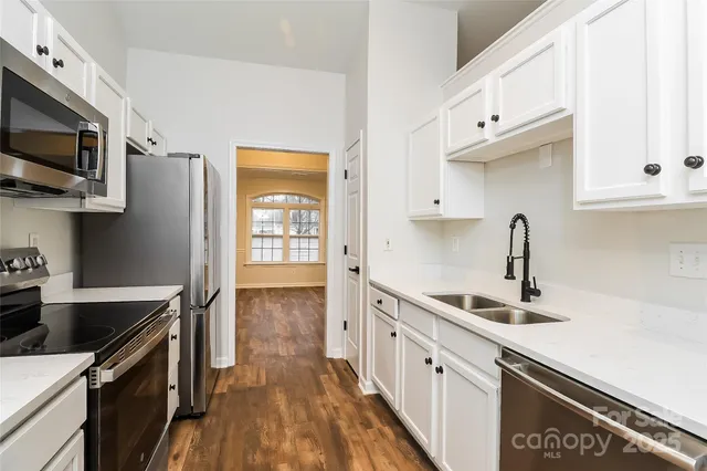 a kitchen with stainless steel appliances a sink dishwasher stove microwave and cabinets with wooden floor